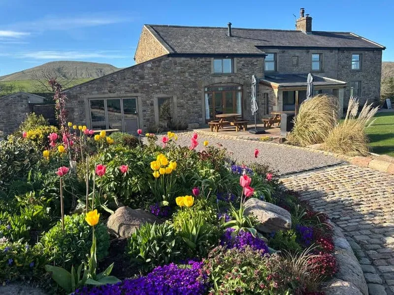 Stone Cuthbert Hill Farm cottage with colourful garden and cobbled path in countryside setting