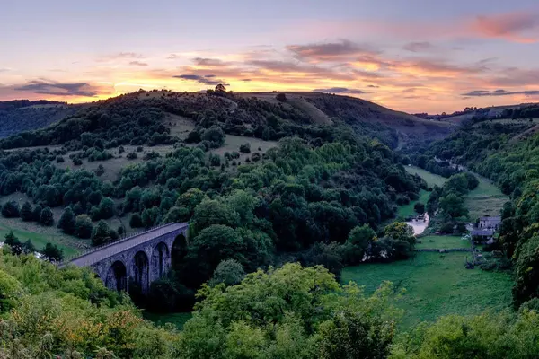 Sunset illuminating the historic Headstone Viaduct and lush green Wye Valley at Monsal Head, Derbyshire.