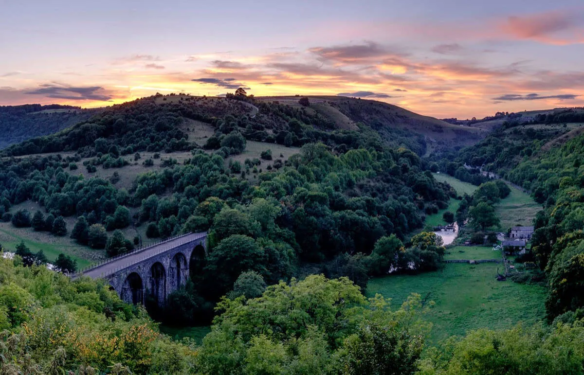 Sunset illuminating the historic Headstone Viaduct and lush green Wye Valley at Monsal Head, Derbyshire.