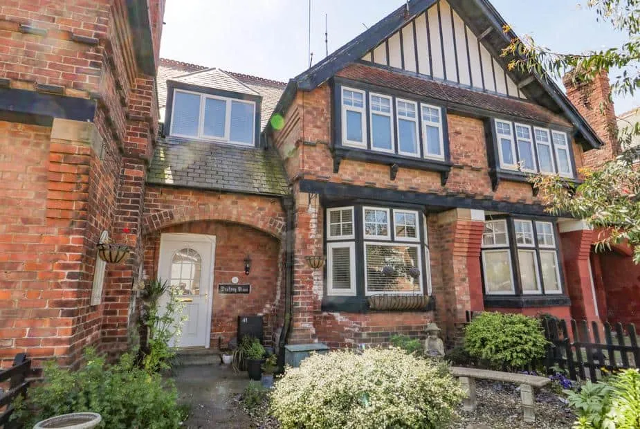 Destiny Rose cottage with red brick facade, bay windows and front garden