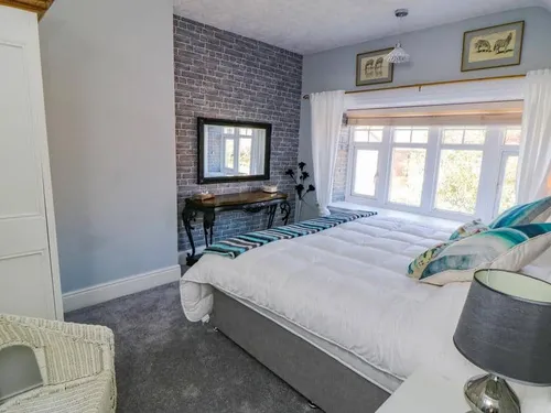 Double bed with white duvet beside large bay window