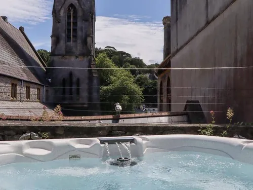 Cottage patio with hot tub and view of stone church building