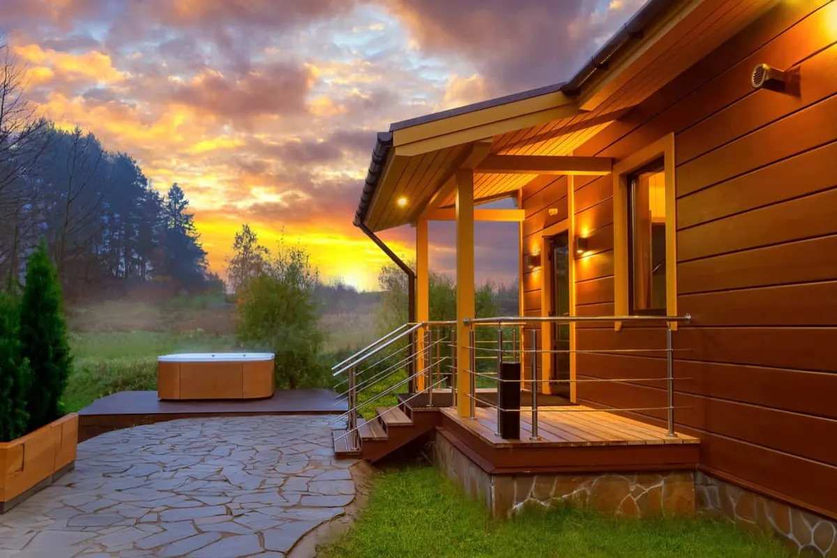 Serene hot tub escape at a modern English cabin during a golden hour sunset.