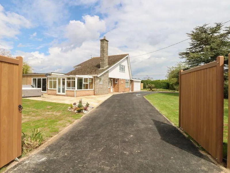 Fallowfield cottage exterior with gated driveway and hot tub on lawn.