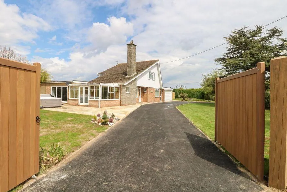 Fallowfield cottage exterior with gated driveway and hot tub on lawn.