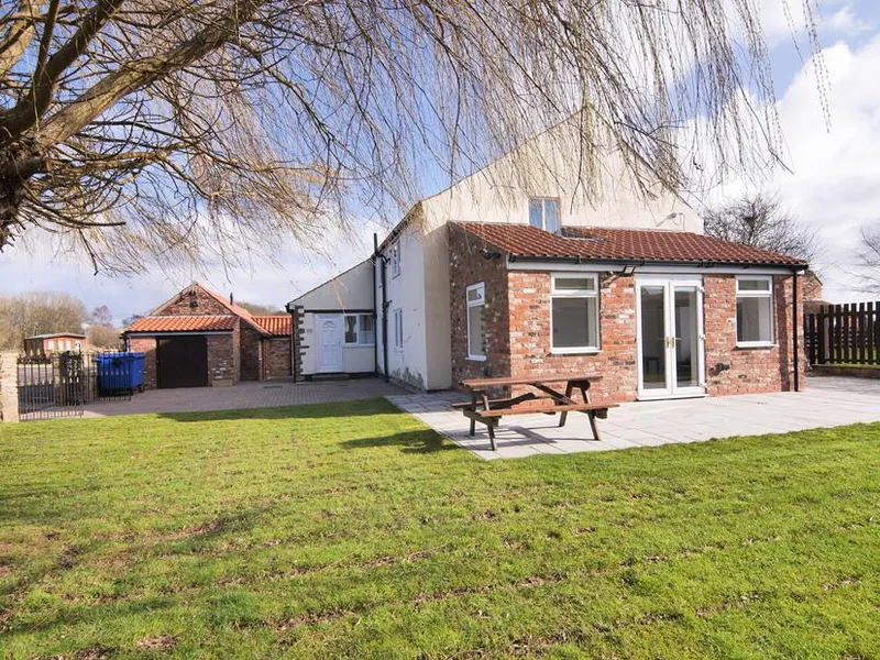 Farmhouse exterior with brick and white render, patio, picnic bench, and lawned garden at Murton Grange