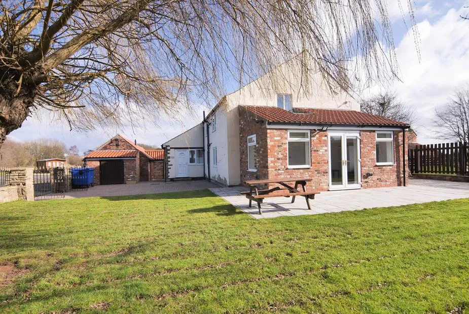 Farmhouse exterior with brick and white render, patio, picnic bench, and lawned garden at Murton Grange