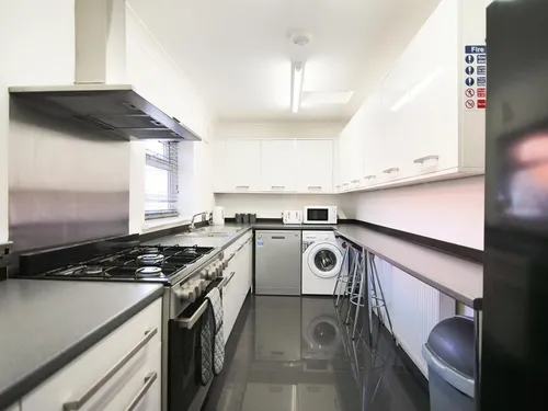 Kitchen with white gloss units, dark worktops, range cooker, stainless steel splashback, and washing machine