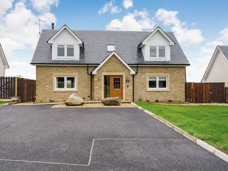 Fiadh Ruadh with gabled roof and driveway, fronted by two large stones