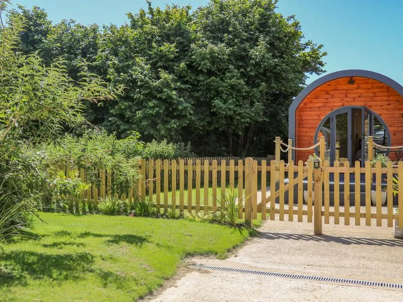 Filbert Pod wooden lodge with arched entrance and fenced garden area in front