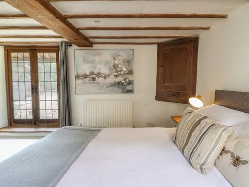 Rustic double bedroom with wooden beams, French doors, and cosy decor