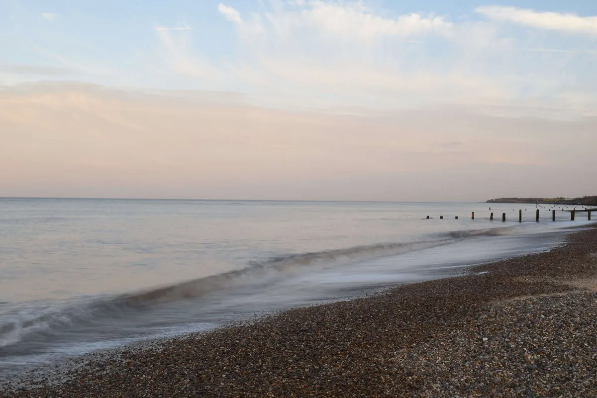 Soft sunset light reflecting on the calm waves and sandy shore of Gorleston Beach, near Great Yarmouth.
