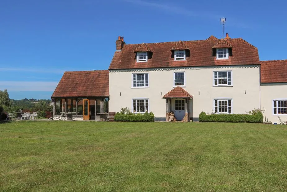 Groomes Country House with red tiled roof and large lawn under blue sky.