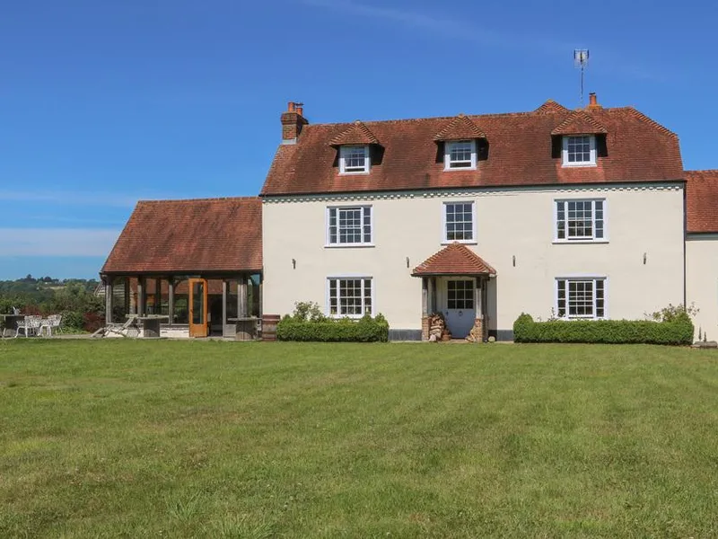 Groomes Country House with red tiled roof and large lawn under blue sky.