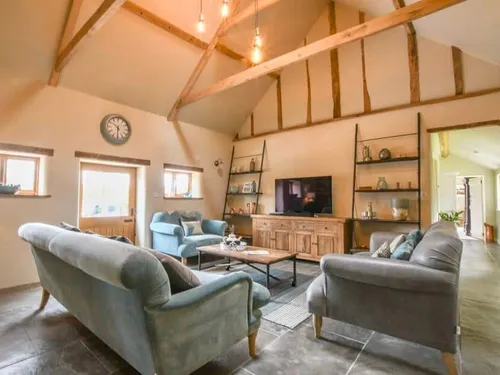 Cottage living room with exposed beams, sofas, and television on wooden unit