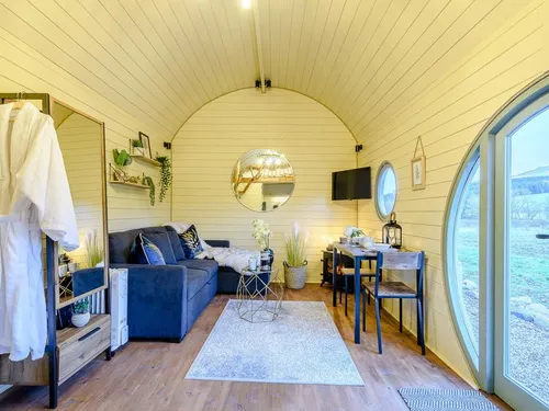 Lodge living area with grey sofa, dining table and round mirror on wall