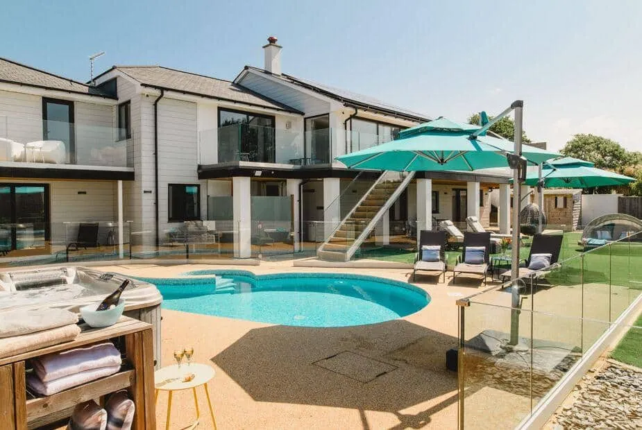 Heron House with outdoor pool, sun loungers, and parasols in a fenced patio area