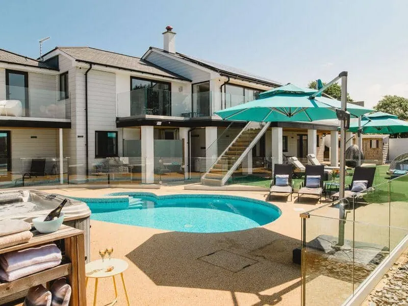 Heron House with outdoor pool, sun loungers, and parasols in a fenced patio area