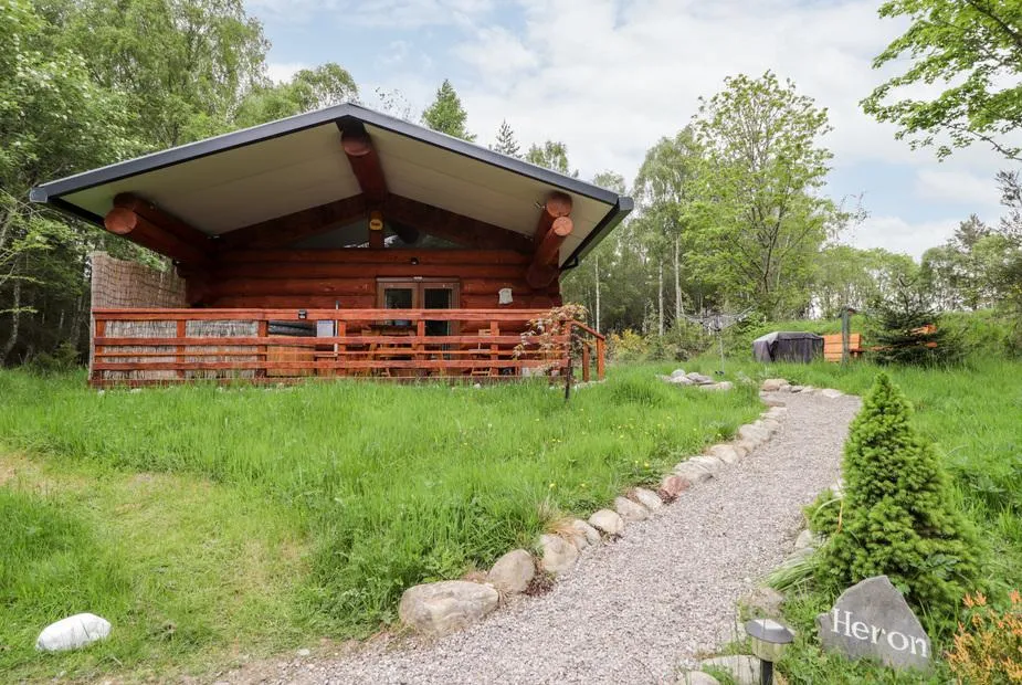 Heron Lodge log cabin with gravel path and woodland setting in Craigbreck Wood