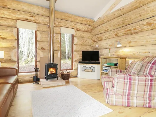 Log cabin living room with wood burner, leather sofa, and tartan armchair