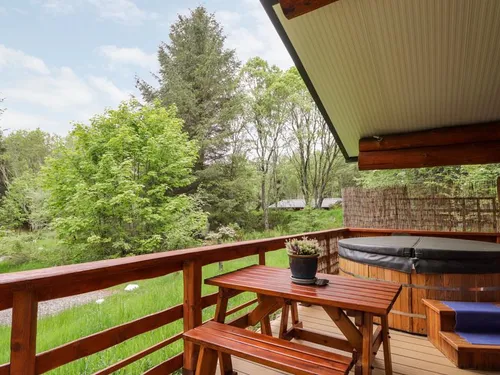 Covered deck with hot tub, picnic table, and woodland views