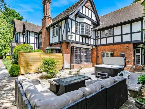 Cottage garden patio with rattan sofa set and hot tub