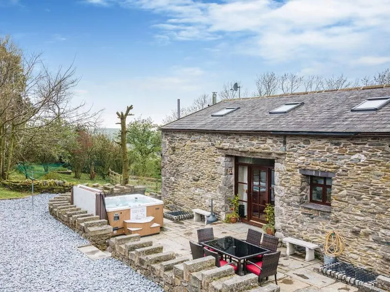Hill Side Barn stone cottage exterior with patio seating and outdoor hot tub