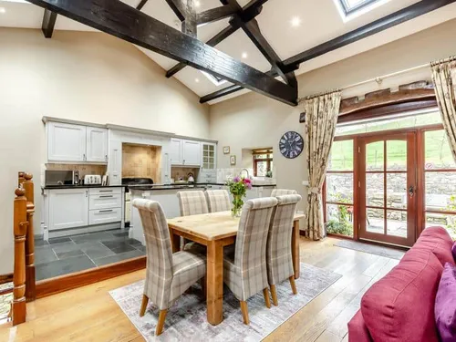 Cottage kitchen and dining area with exposed beams and French doors to garden