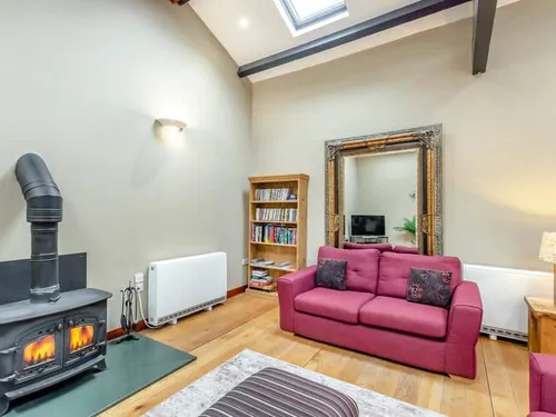 Cottage lounge with log burner, red sofa and bookcase