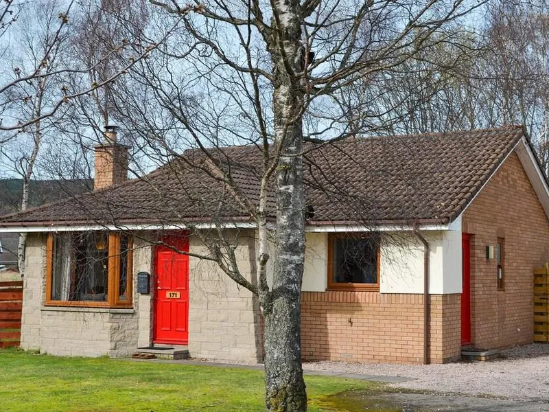 Holly Lodge exterior with red doors and a tree in the front garden