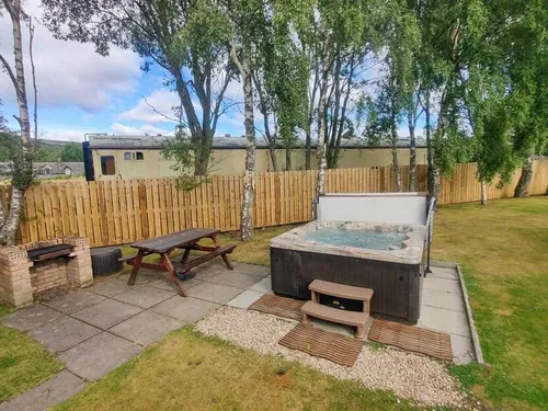 Lodge garden with hot tub, picnic bench and brick barbecue