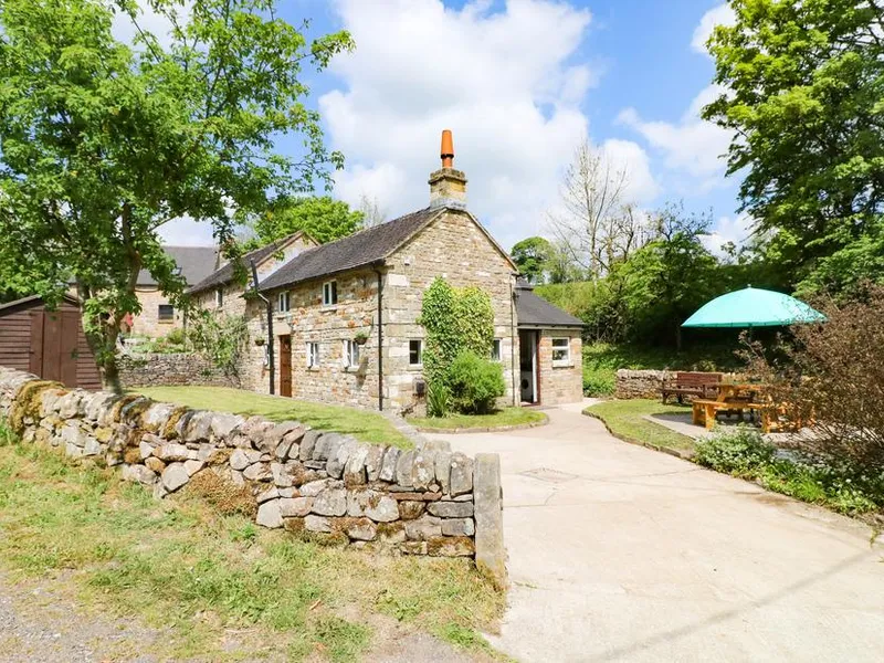 Hoobrook Cottage with stone walls and outdoor seating area under a green parasol