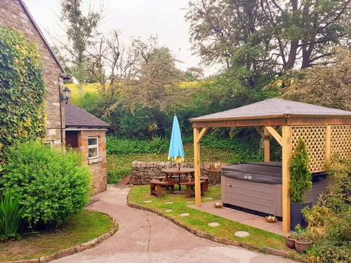Cottage garden with wooden gazebo, hot tub and picnic table with umbrella