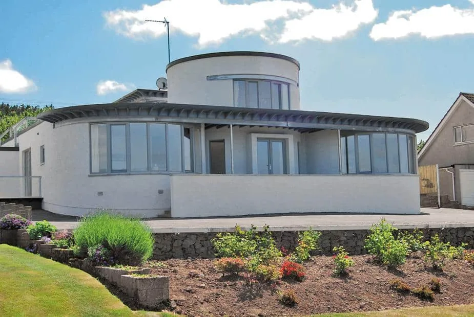 Island View with curved windows and wraparound patio overlooking a landscaped garden.