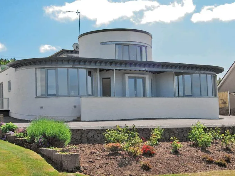 Island View with curved windows and wraparound patio overlooking a landscaped garden.