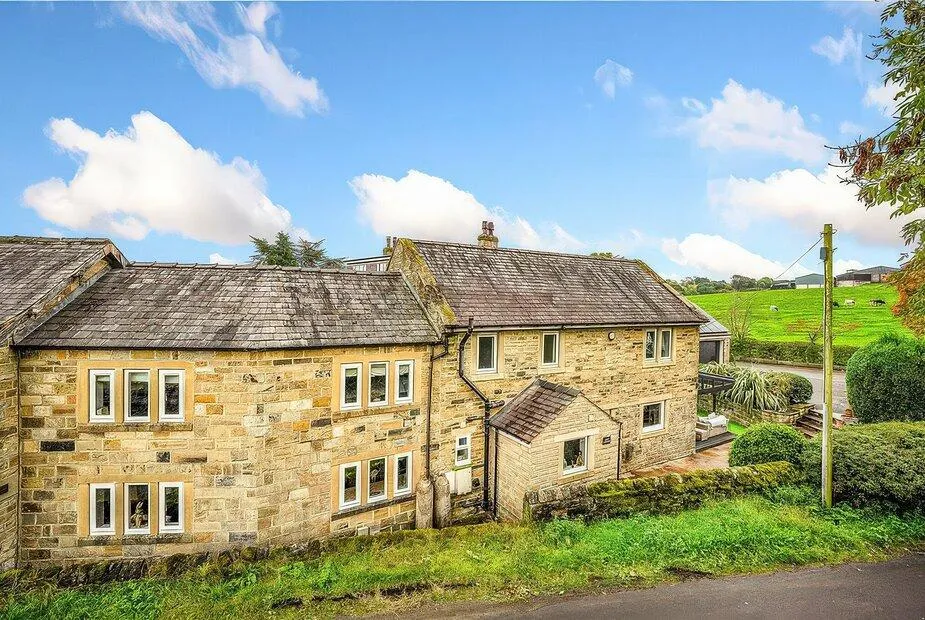 Johns Cottage honey stone exterior with slate roof and green fields rising behind near Hampsthwaite