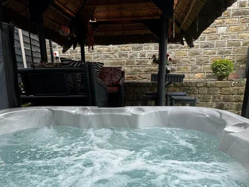 Hot tub bubbling in the enclosed courtyard with the thatched tiki bar and cushioned seating behind