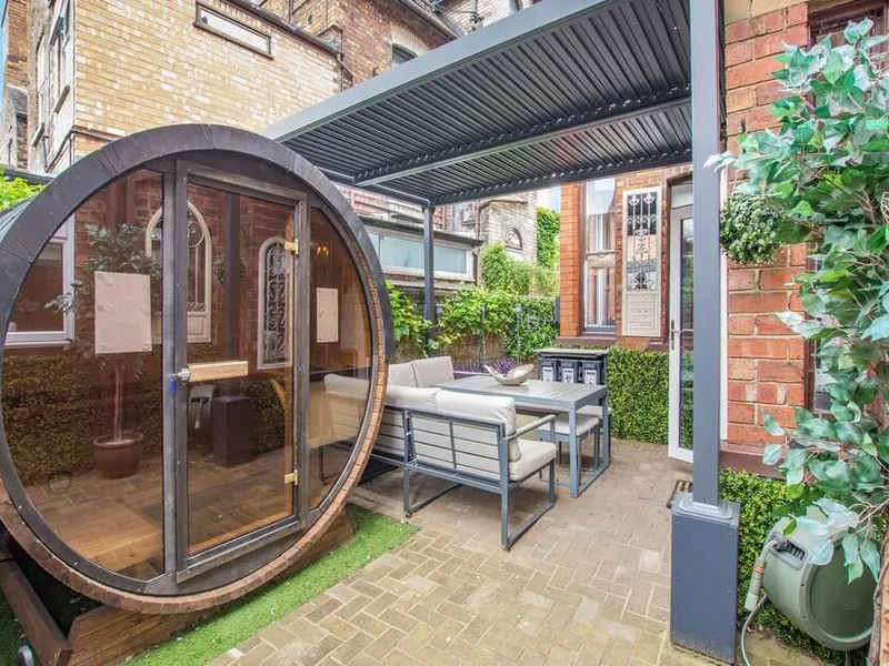 Barrel sauna and outdoor seating under a louvred pergola in Jorvik Villas' enclosed courtyard