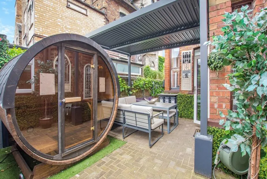 Barrel sauna and outdoor seating under a louvred pergola in Jorvik Villas' enclosed courtyard