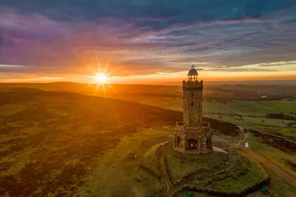 Golden sunset creates a dramatic sunburst behind Darwen Tower, overlooking the rolling Lancashire countryside.