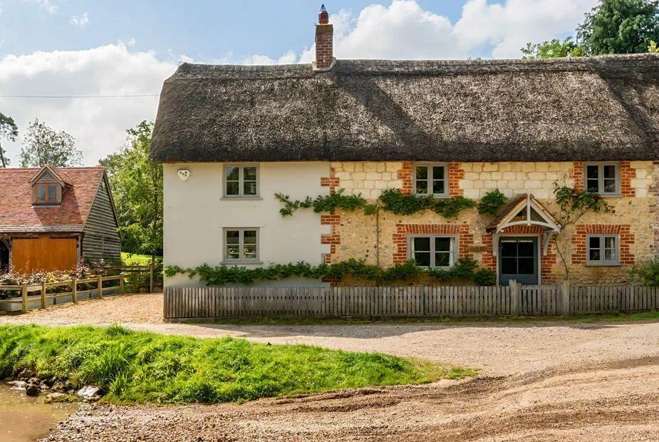 Thatched Lanes End Cottage with climbing plants and front picket fence in Dorchester