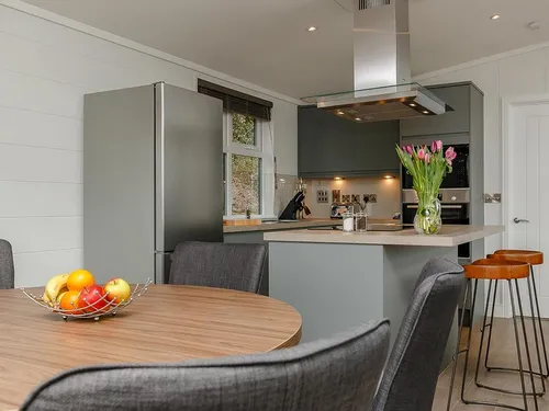 Open-plan kitchen and dining area with grey cabinets, breakfast bar, and round dining table