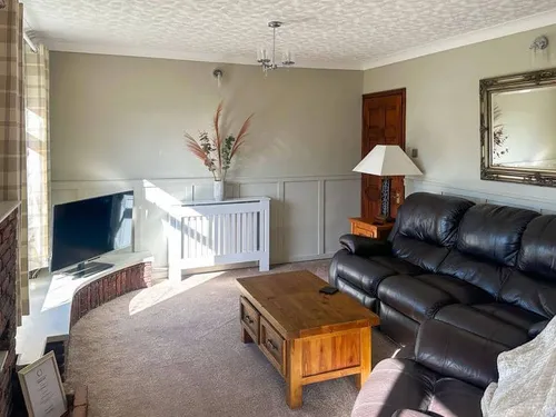Lodge living room with black leather sofa, wooden coffee table and TV in corner
