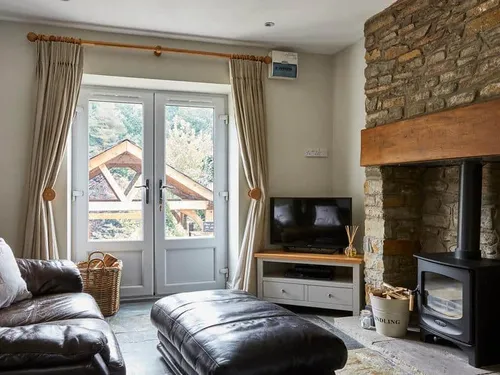 Cottage lounge with wood burner, stone fireplace, and double doors to garden.