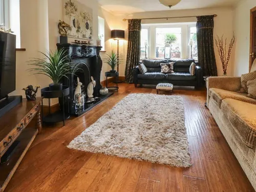Cottage living room with fireplace, two sofas and a large rug on wooden floor