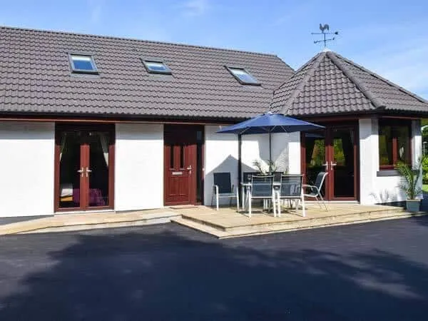 Little Chestnut exterior with outdoor seating area and parasol on paved patio