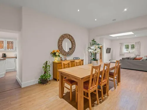 Dining area with six chairs in open-plan cottage next to lounge and kitchen