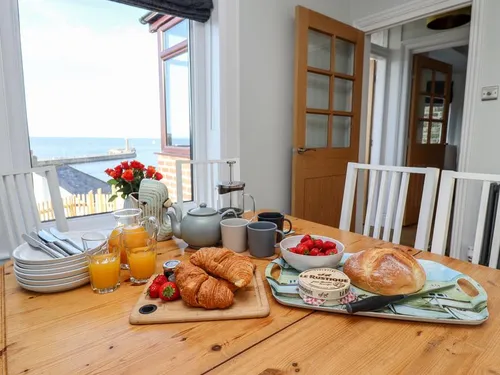 Pine dining table with breakfast spread and sea views through the window towards Whitby pier