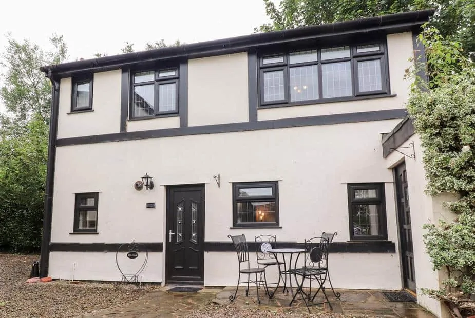 Mayfield Cottage exterior with black trim and a small patio table and chairs by the entrance.