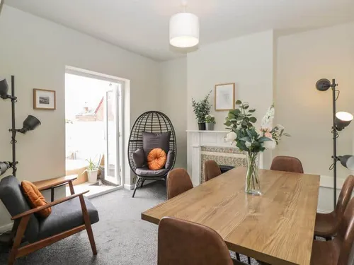 Cottage dining room with wooden table, armchairs and egg chair by patio doors